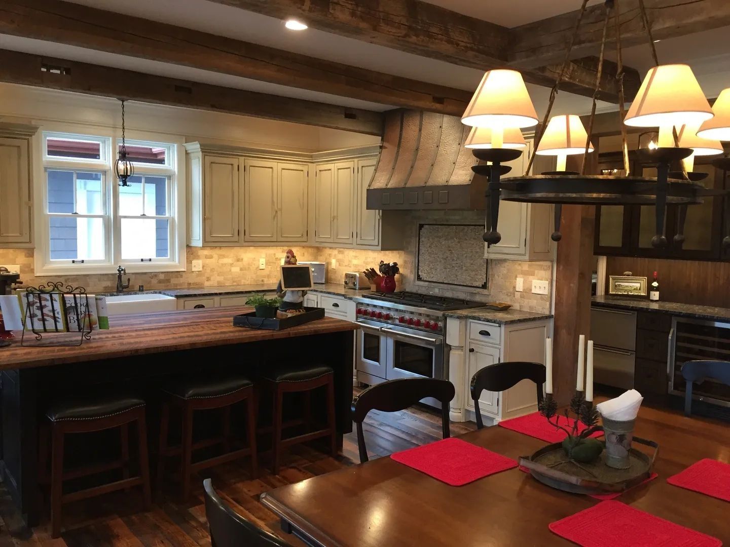 Kitchen with wooden beams, island, cabinets, a stove, and a dining table set.