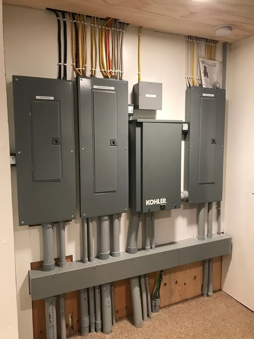 Electrical panel setup with gray panels and conduit on a wall.
