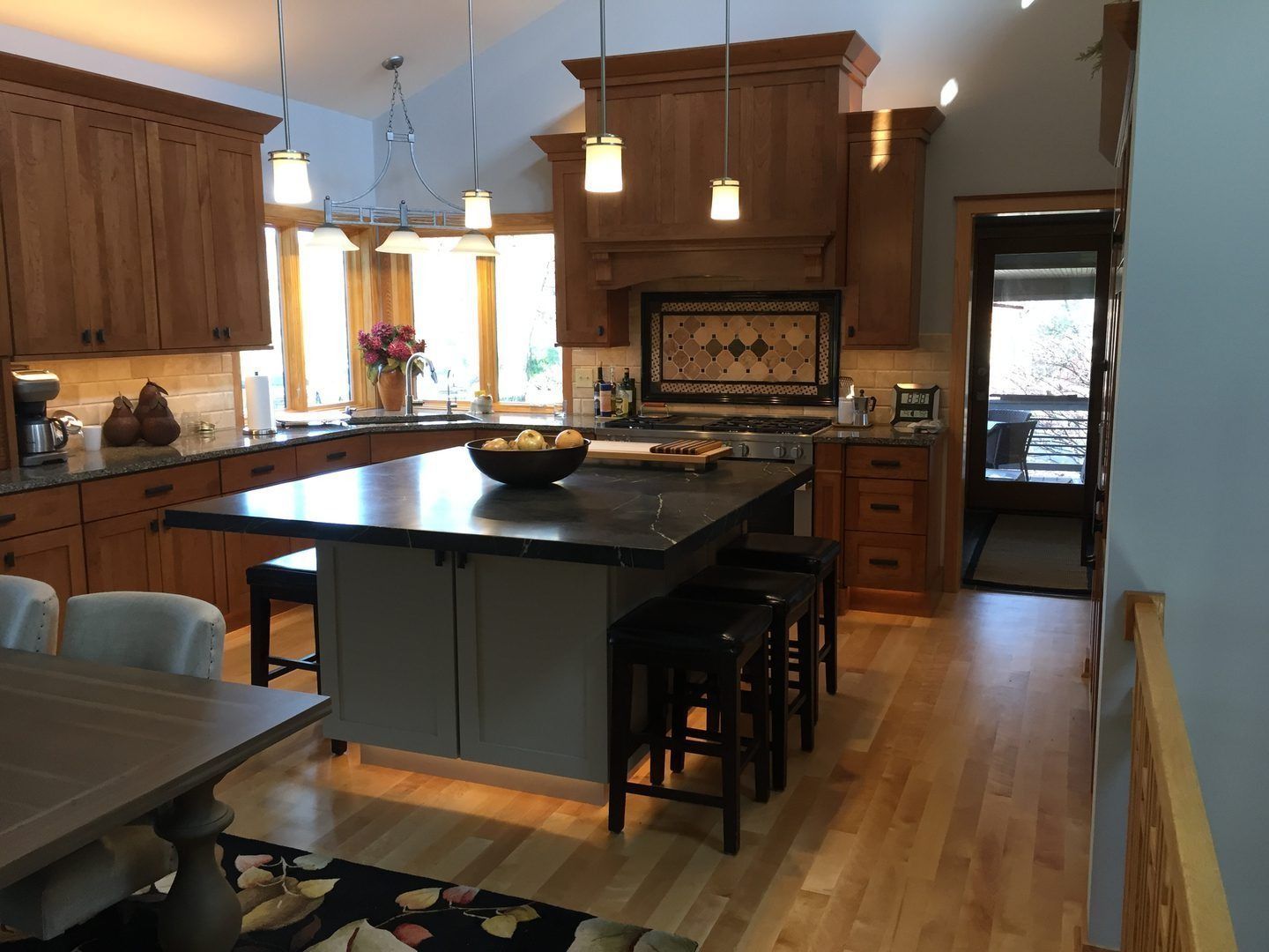 Kitchen with wooden cabinets, island with stools, and open doorway.