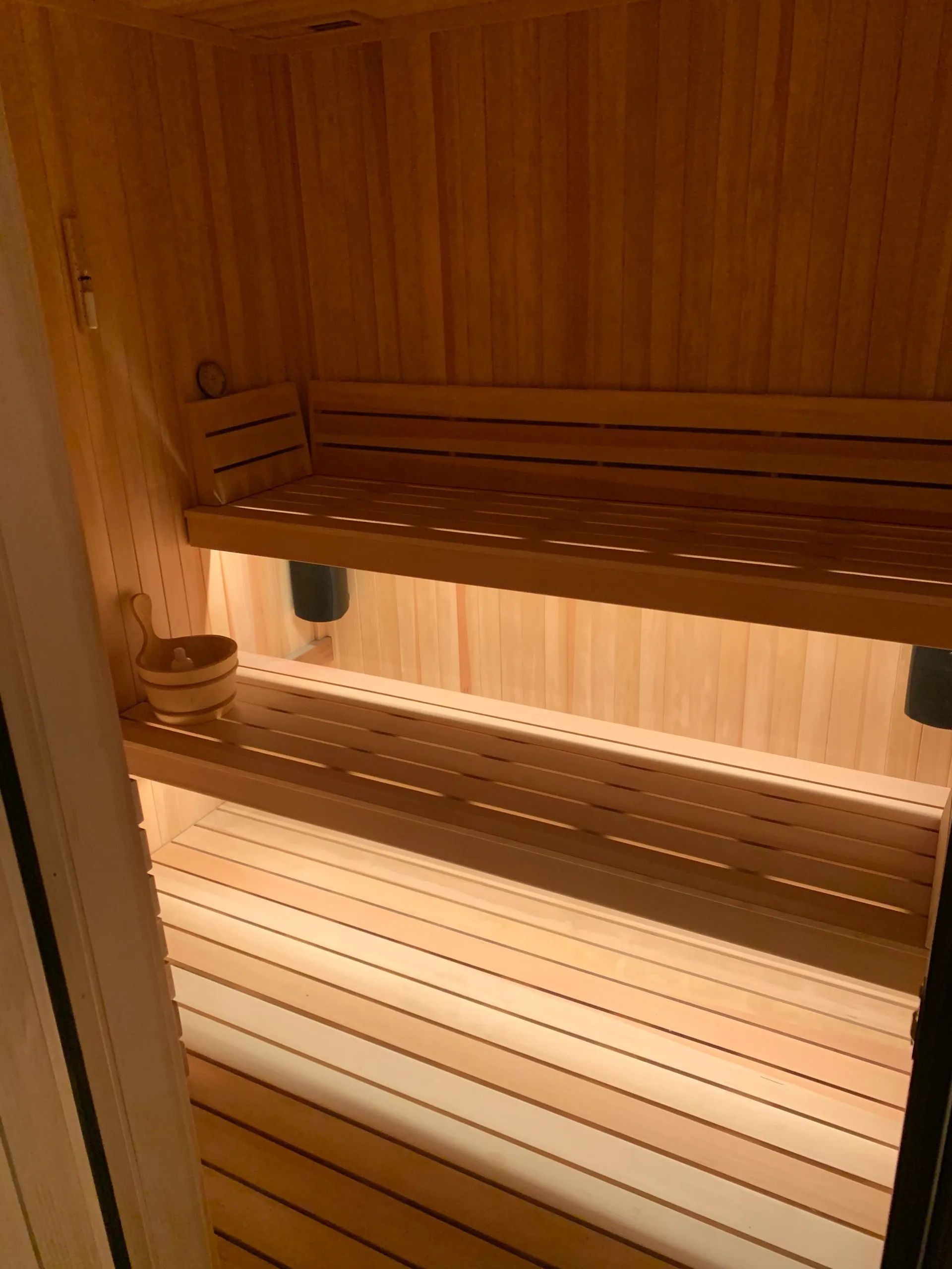 Wooden sauna interior with two-tiered benches and ambient lighting.