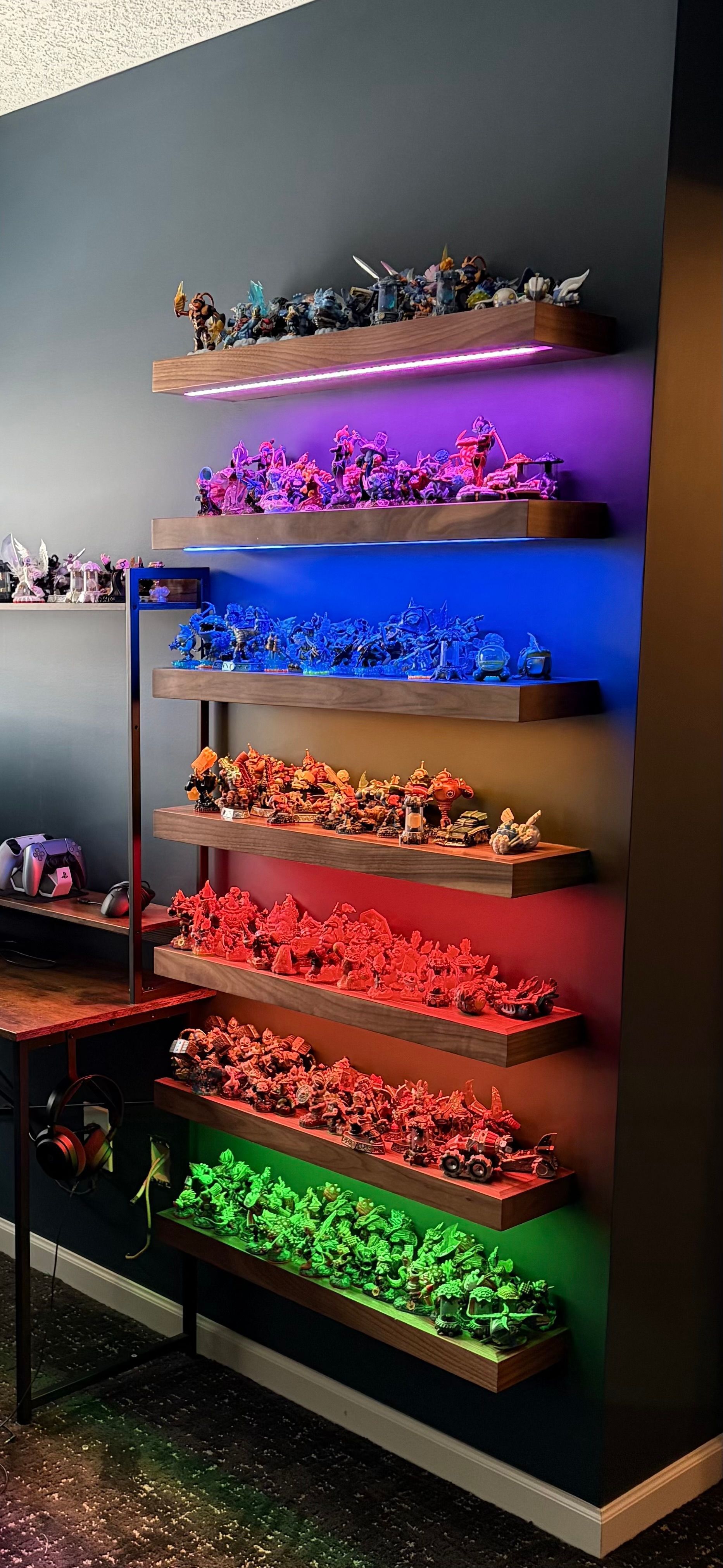 A series of floating shelves displaying figurines, each shelf lit with a different color; green, red, orange, blue, and purple.