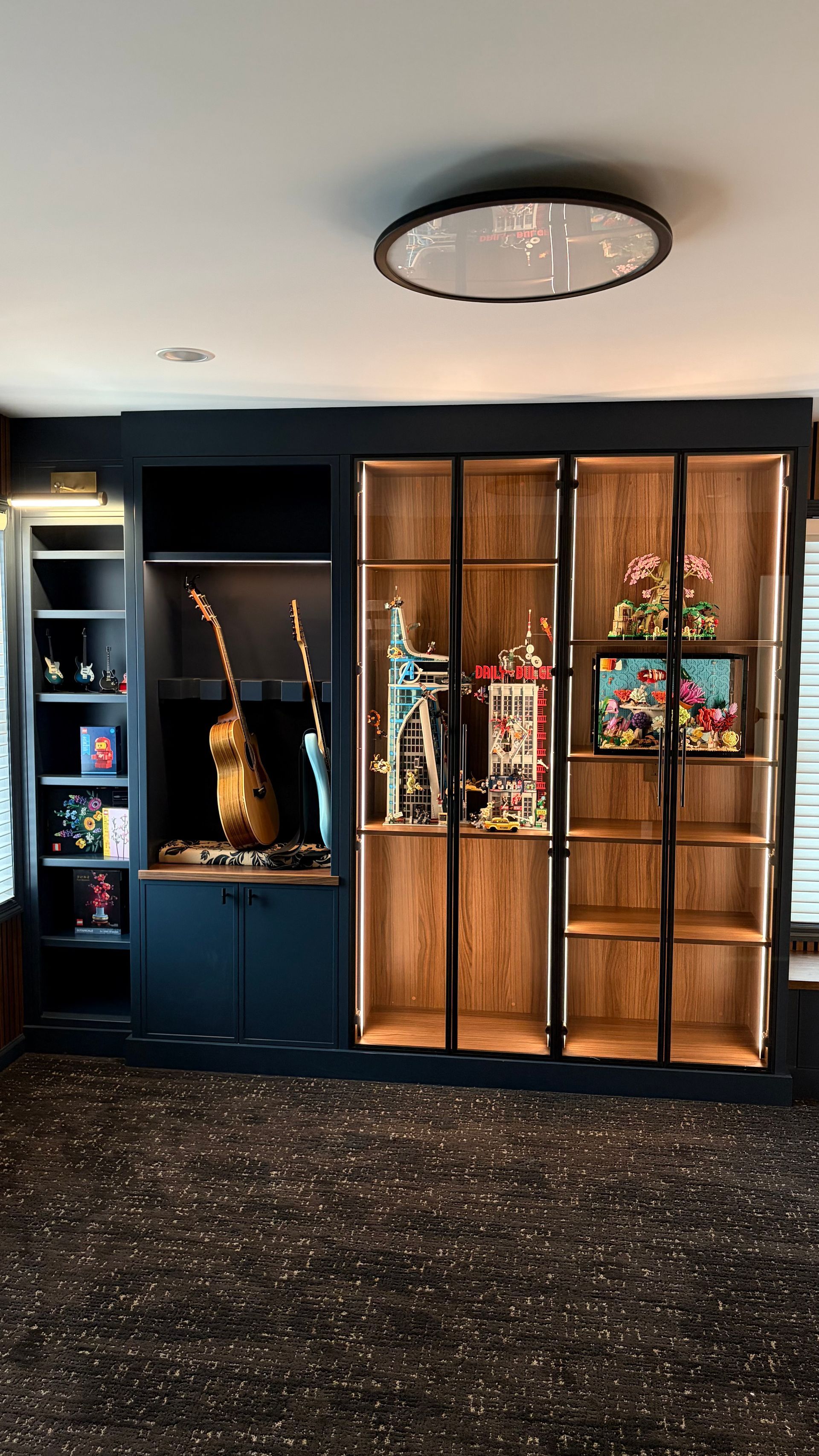 Built-in display cabinet with trophies, guitar, and other items, with black and wood tones.