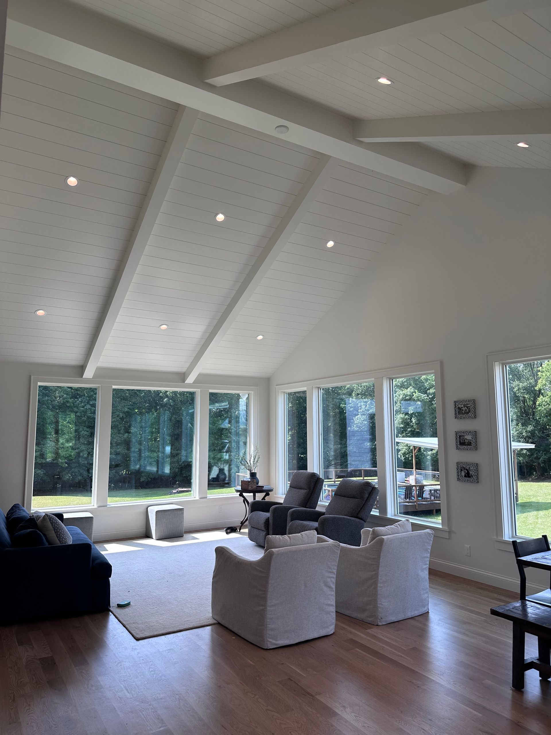 Bright, airy living room with vaulted ceiling, large windows, and modern furniture.
