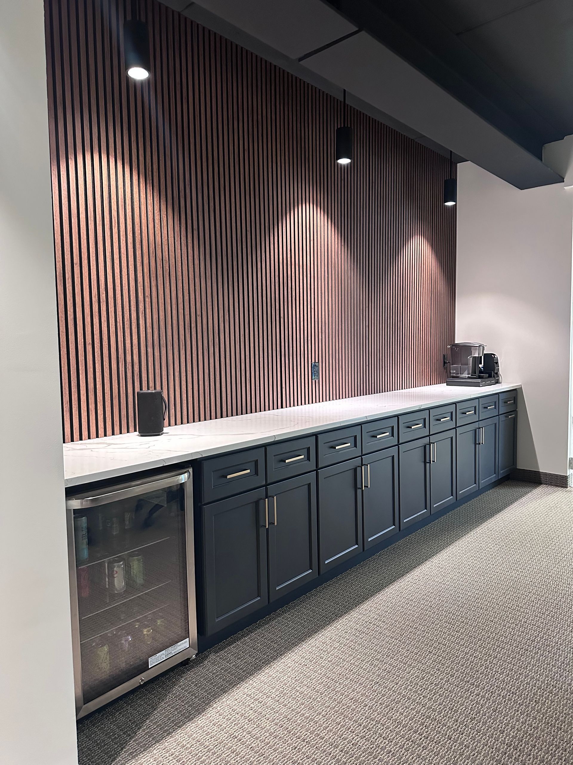 Bar area with dark cabinets, a wine fridge, and a textured wall with recessed lighting.