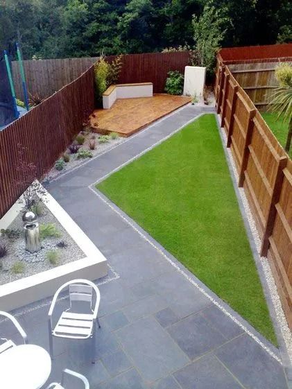 Backyard garden with gray patio, green lawn, raised beds, and wooden fences