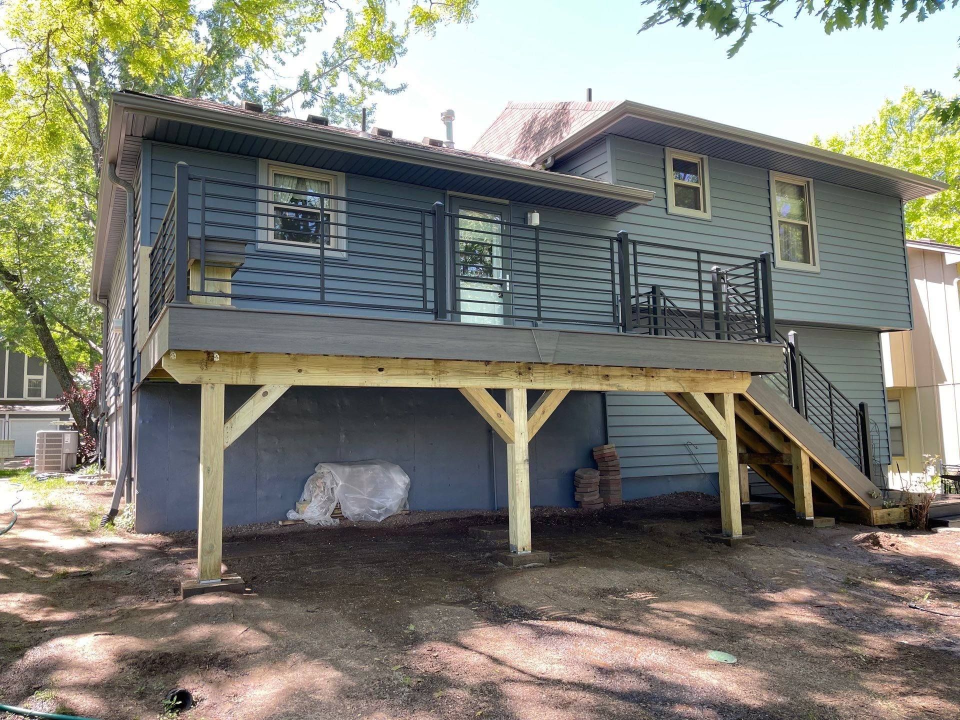 The back of a house with a wooden deck and stairs.