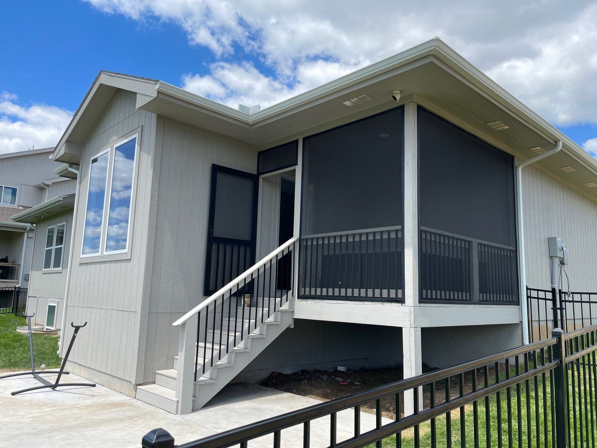 A white house with a screened in porch and stairs.