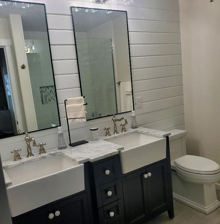 A bathroom with two sinks, two mirrors and a toilet