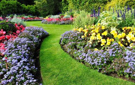 Lush garden with a winding green path flanked by colorful flower beds.