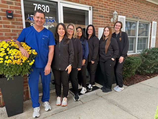 A group of people wearing scrubs and standing outside a building with the number 7630 on the door.