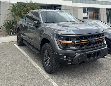 Black pickup truck parked outside a building, front three-quarter view.