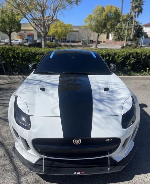 White sports car with a black center stripe parked outdoors, front view