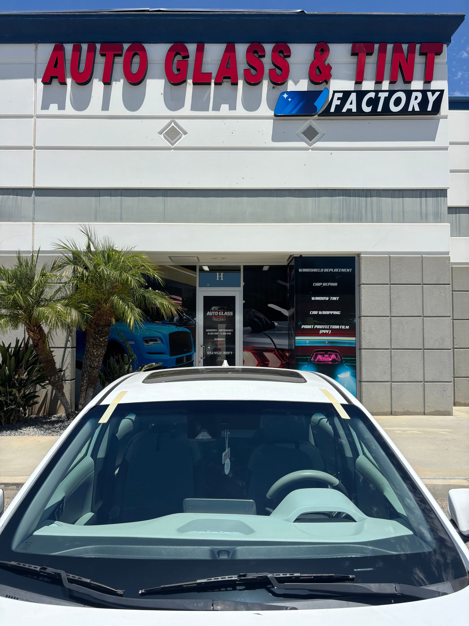 Auto Glass & Tint Factory storefront with a parked car in front of the entrance