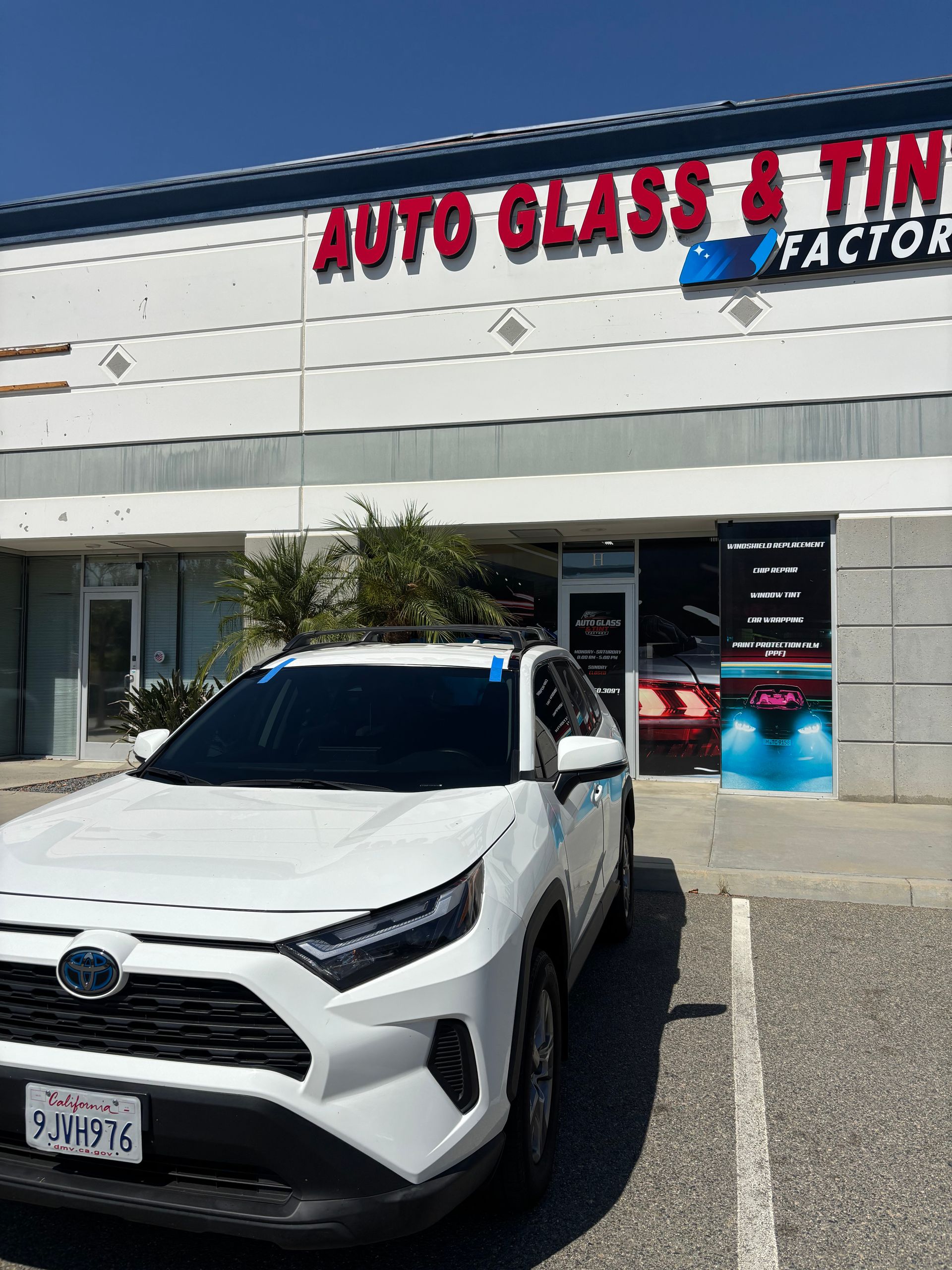 White SUV parked outside an Auto Glass & Tint storefront