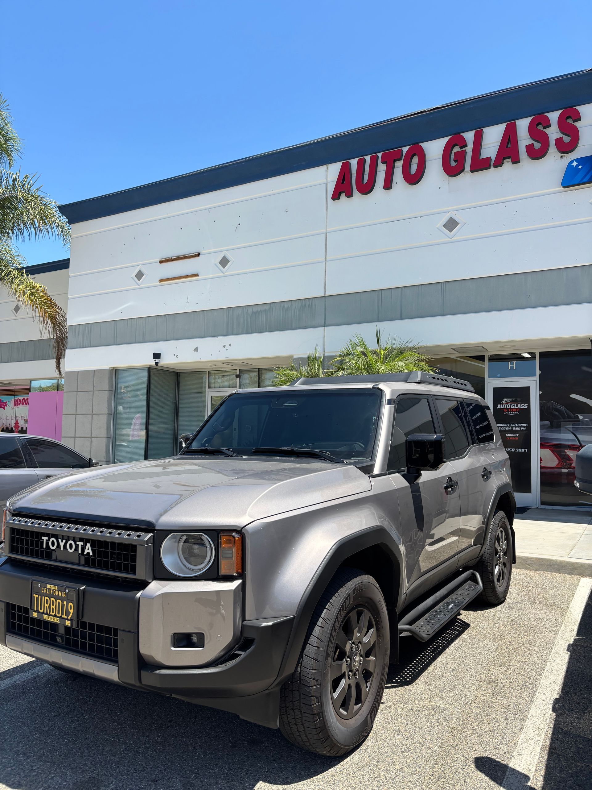 Black SUV parked outside an auto glass shop on a sunny day