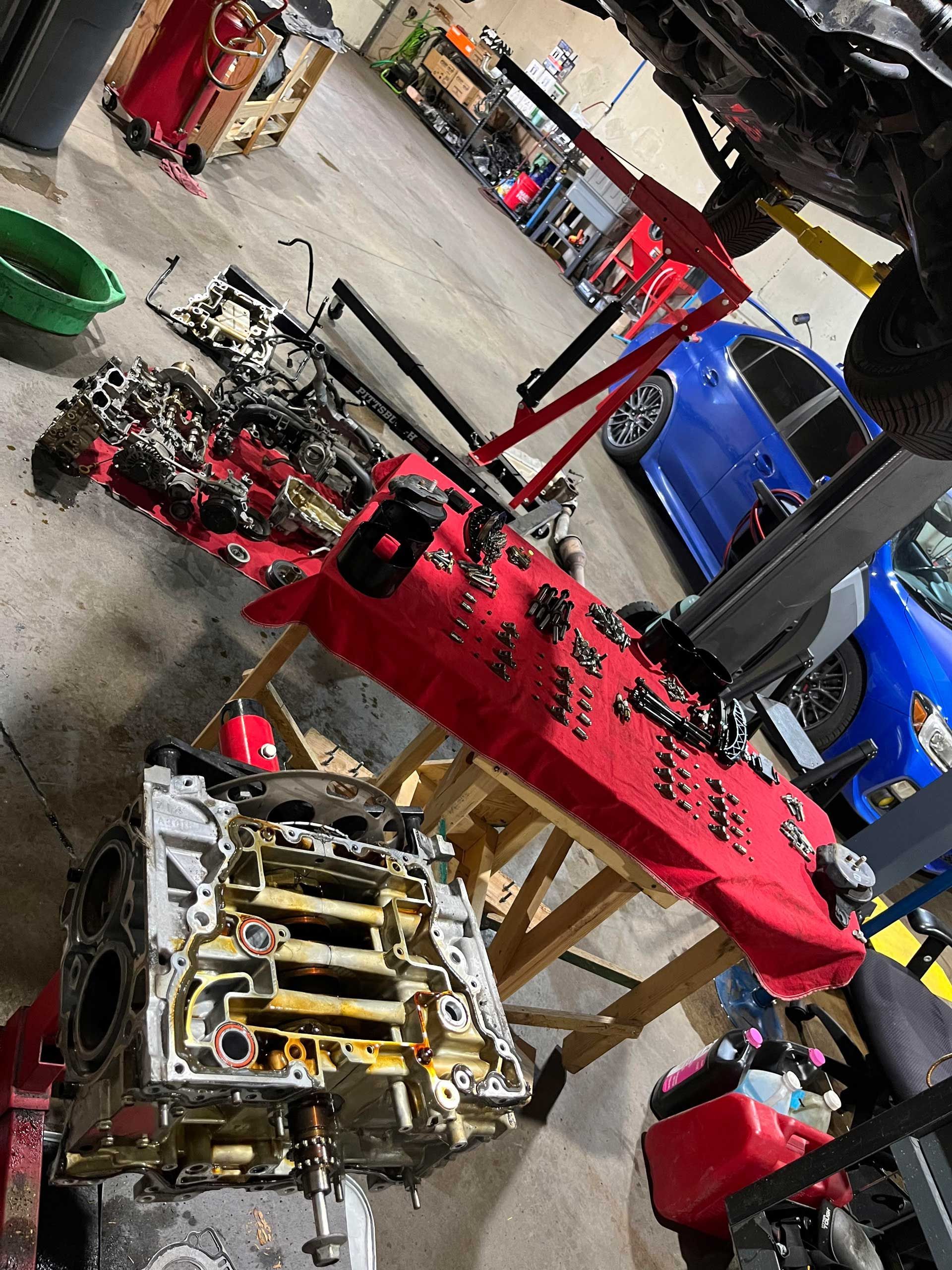 Workshop scene with red engine parts and a disassembled transmission on the floor