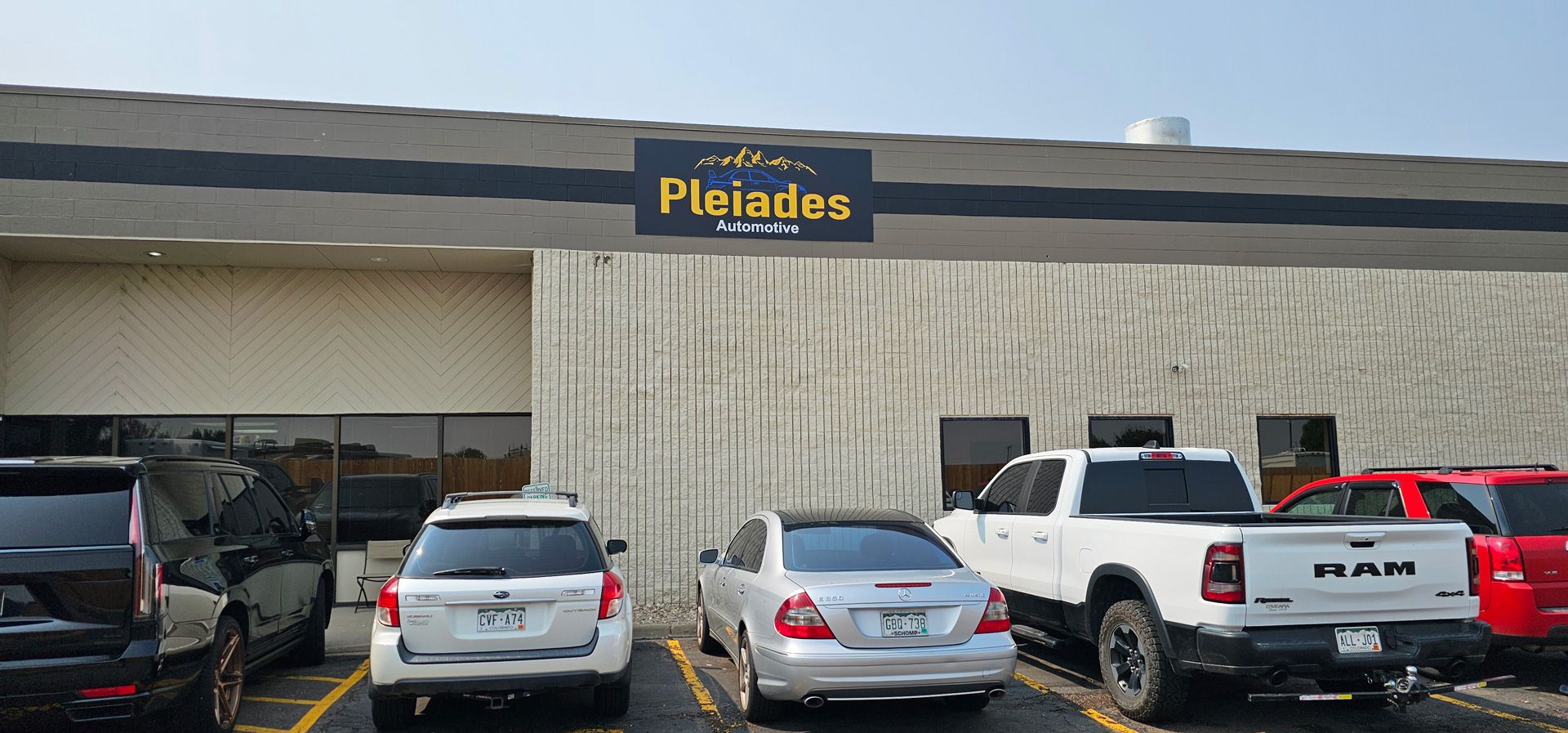 Pleiades storefront with parked cars and a white pickup in front