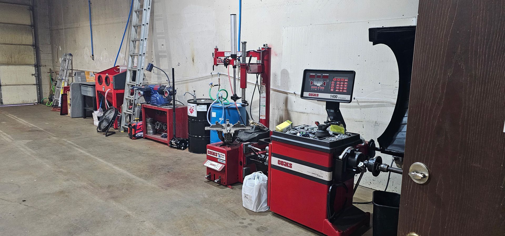 Row of red industrial machines and tanks along a warehouse wall on a concrete floor