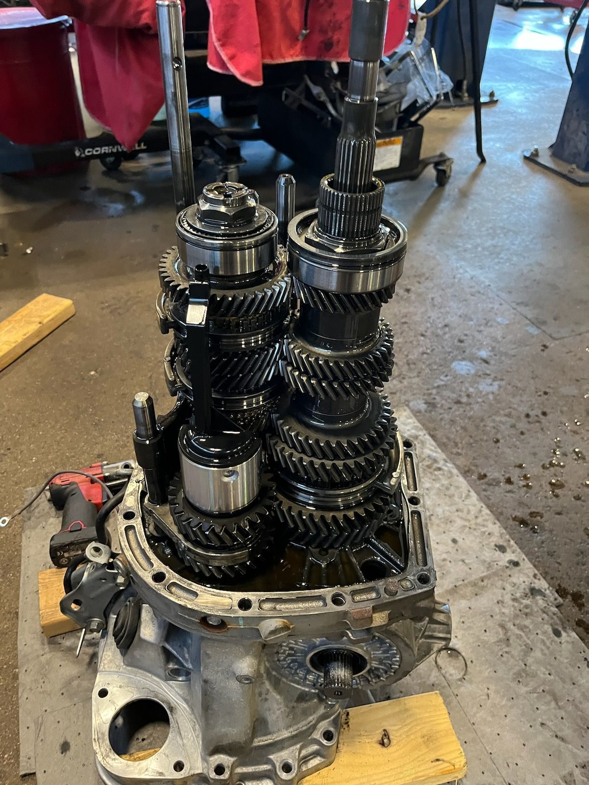 Open transmission gearbox with exposed gears and shafts on a workshop floor
