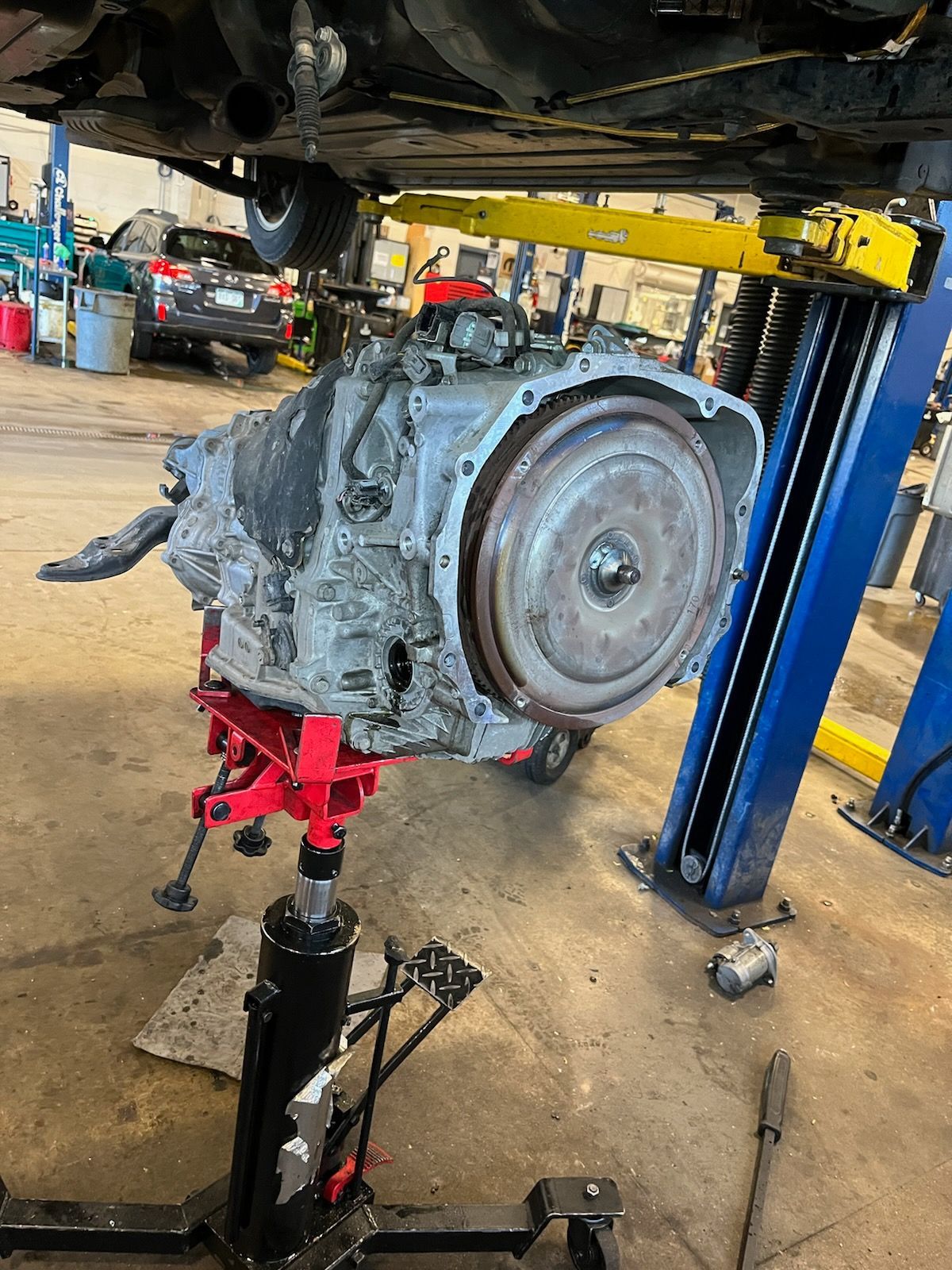 Car engine on a red and black engine stand in an auto repair shop, viewed from the side
