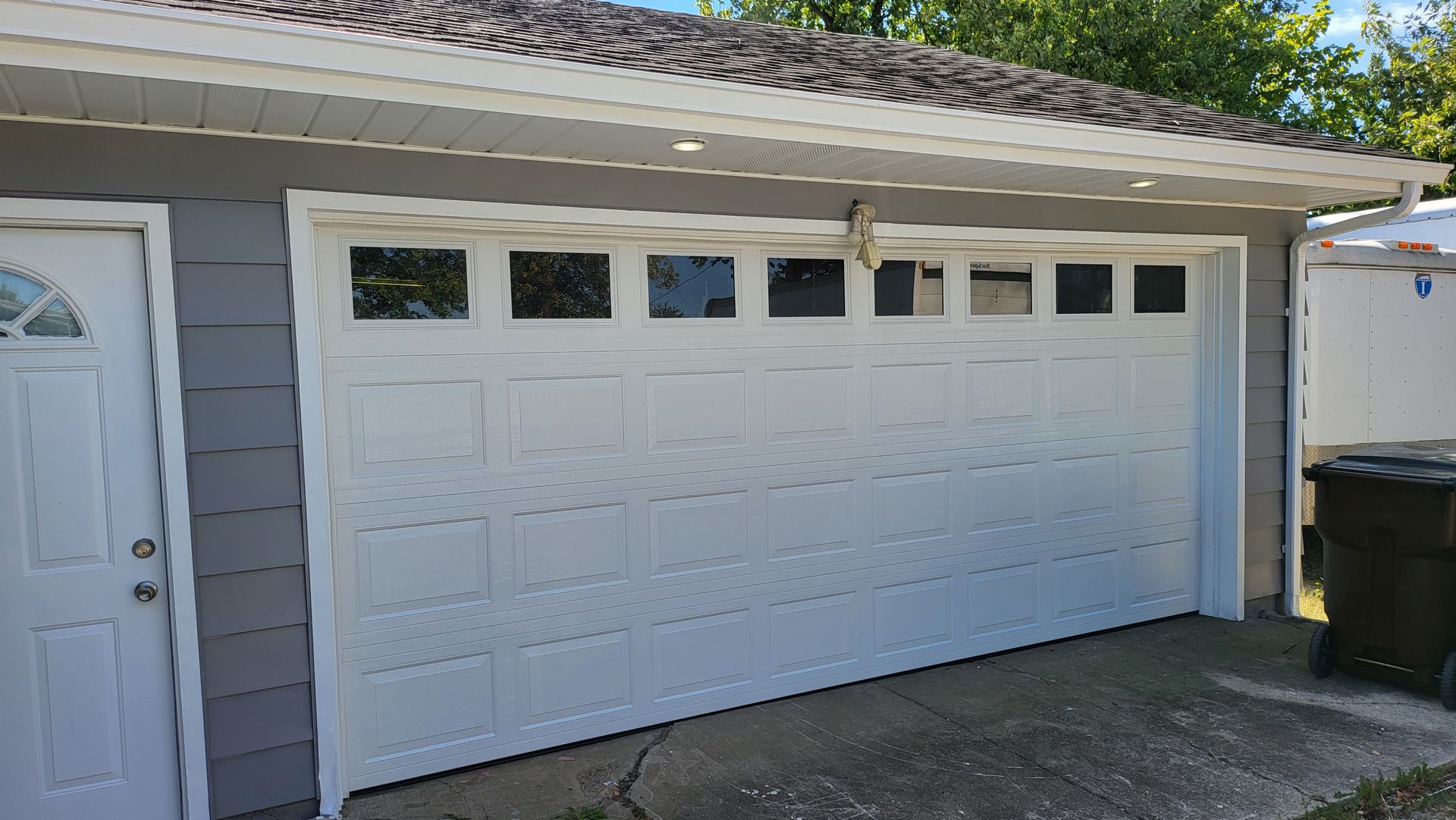 A white garage door is sitting on the side of a house.