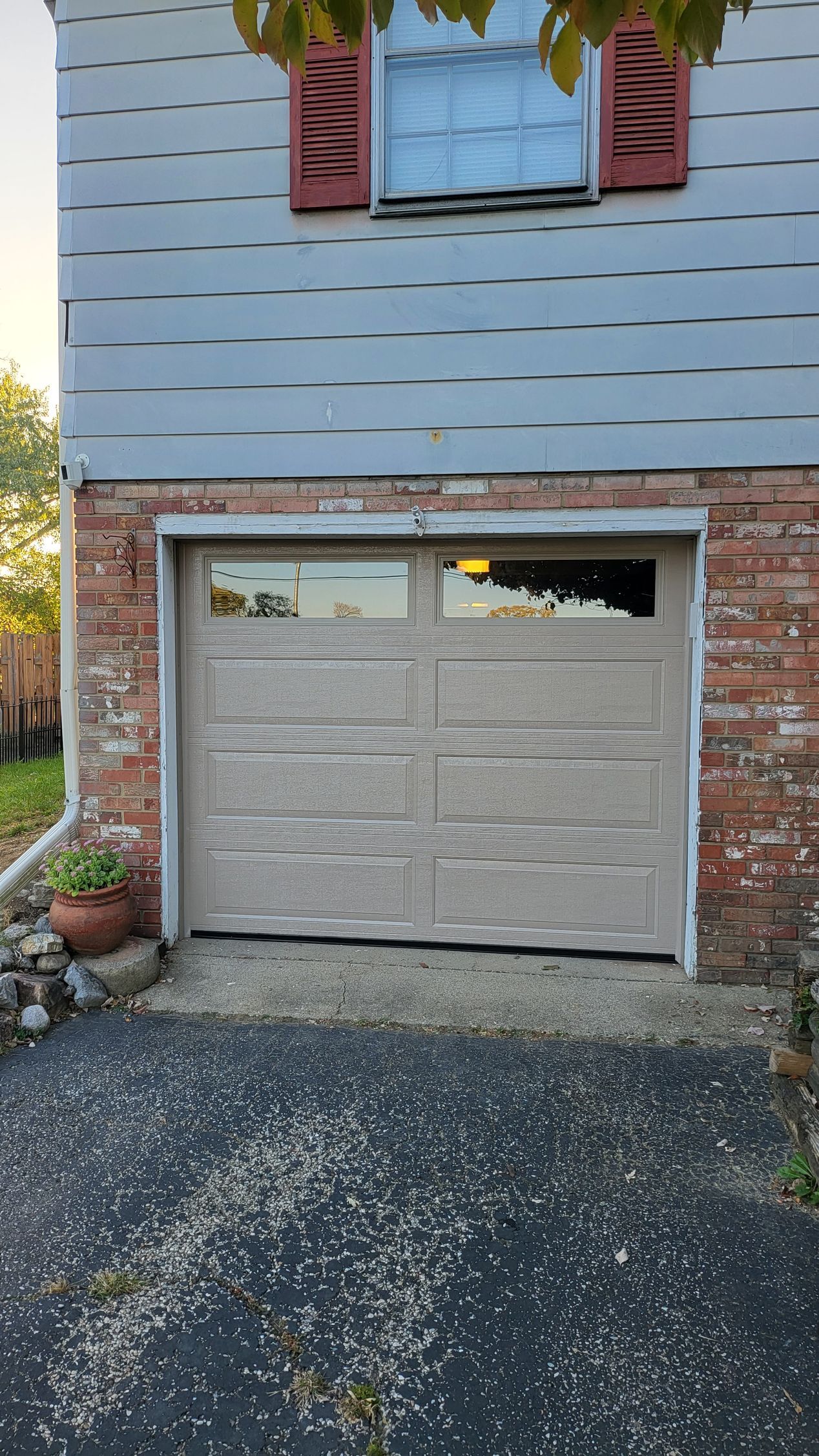 A garage door is open in front of a brick house.