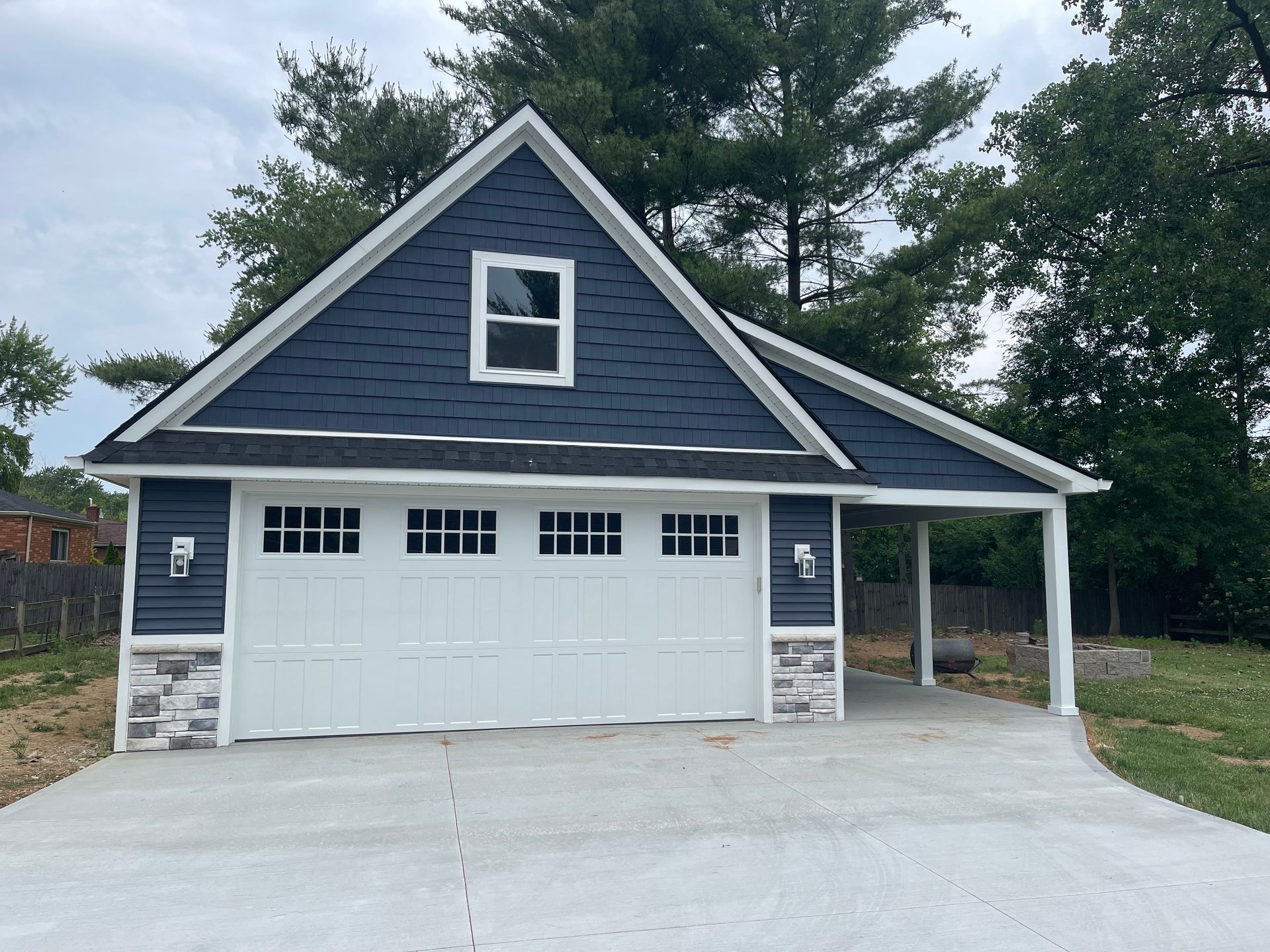 A blue house with a white garage door and a carport