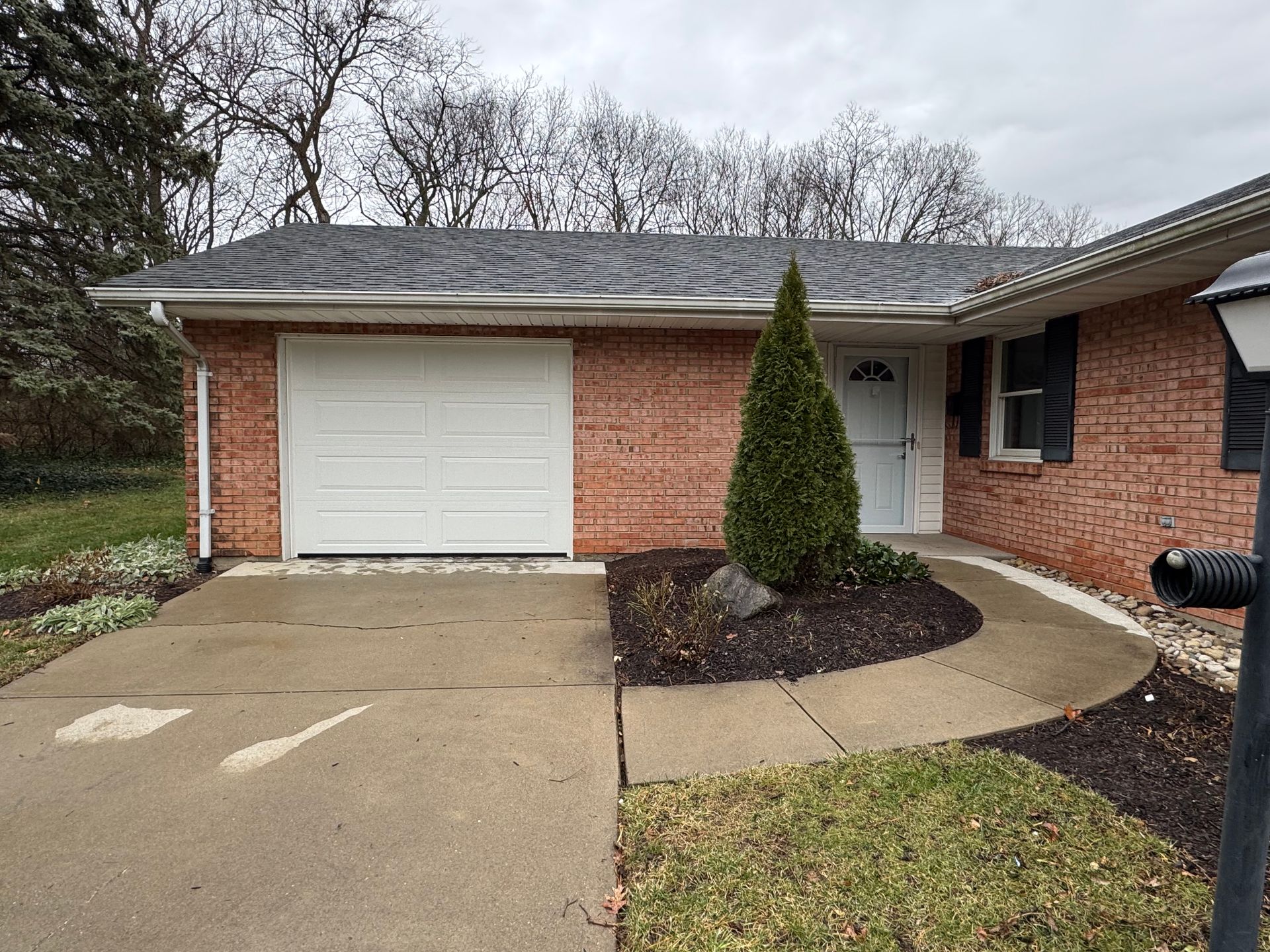 A brick house with a white garage door and a walkway leading to it.