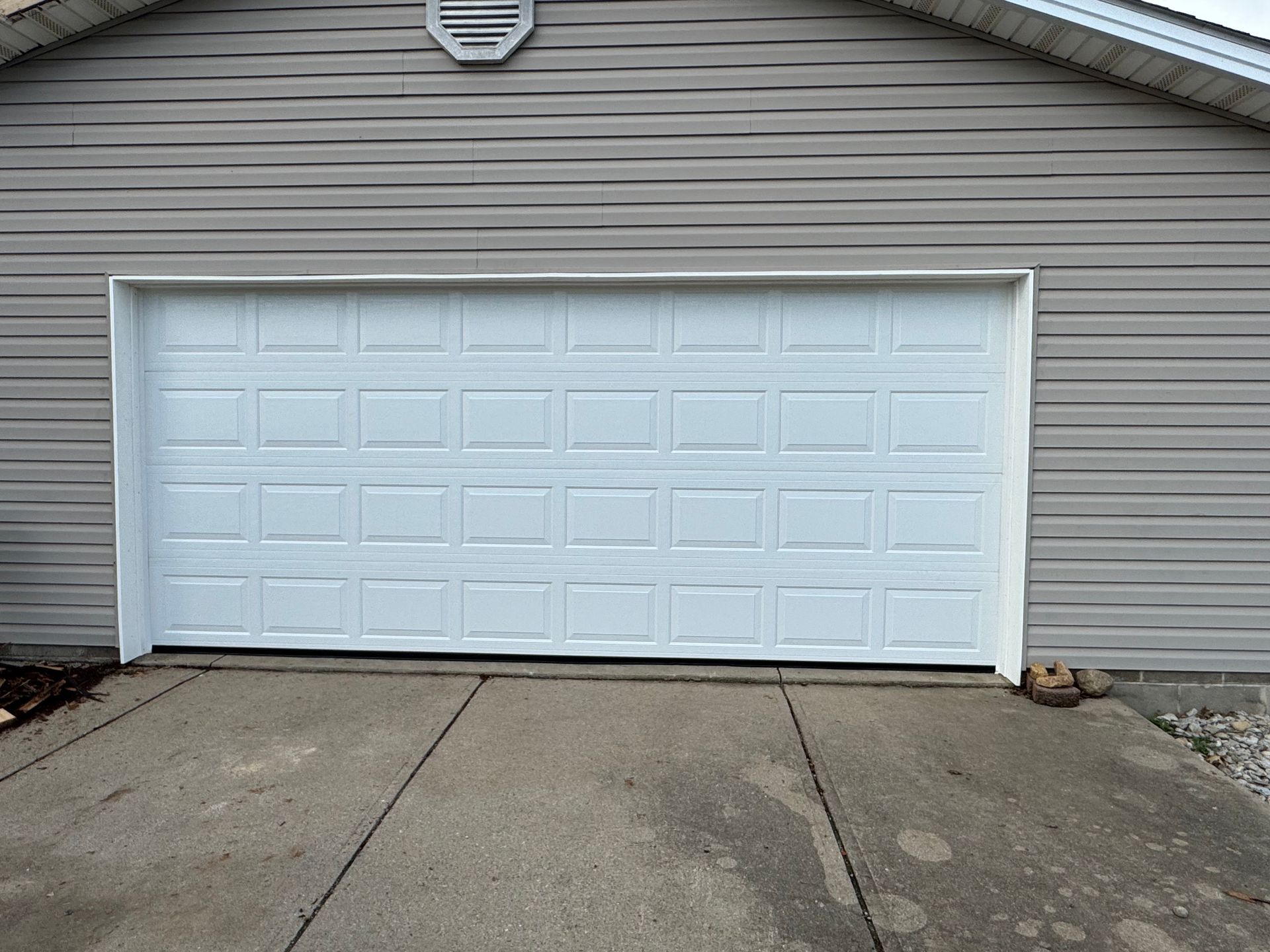 A white garage door is open in front of a house.