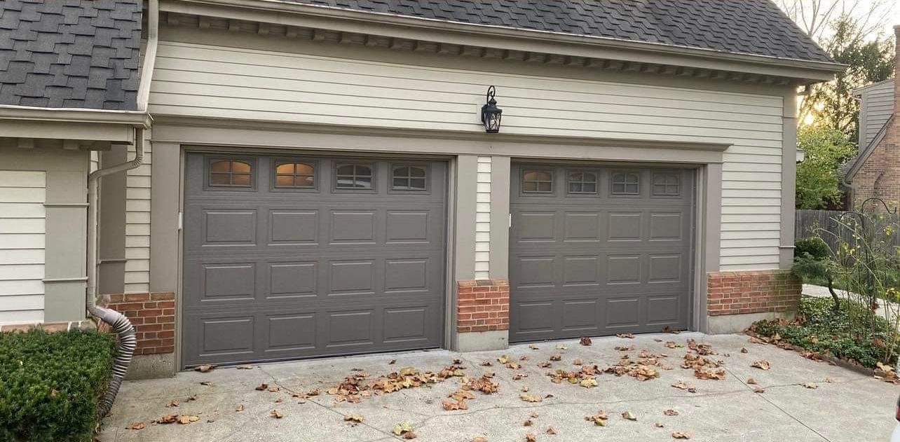 There are two garage doors on the side of a house.