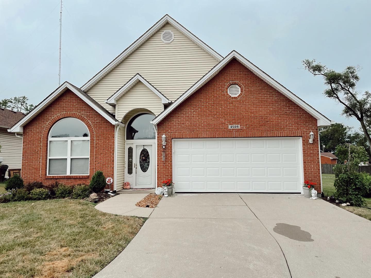 A brick house with a white garage door and a concrete driveway.
