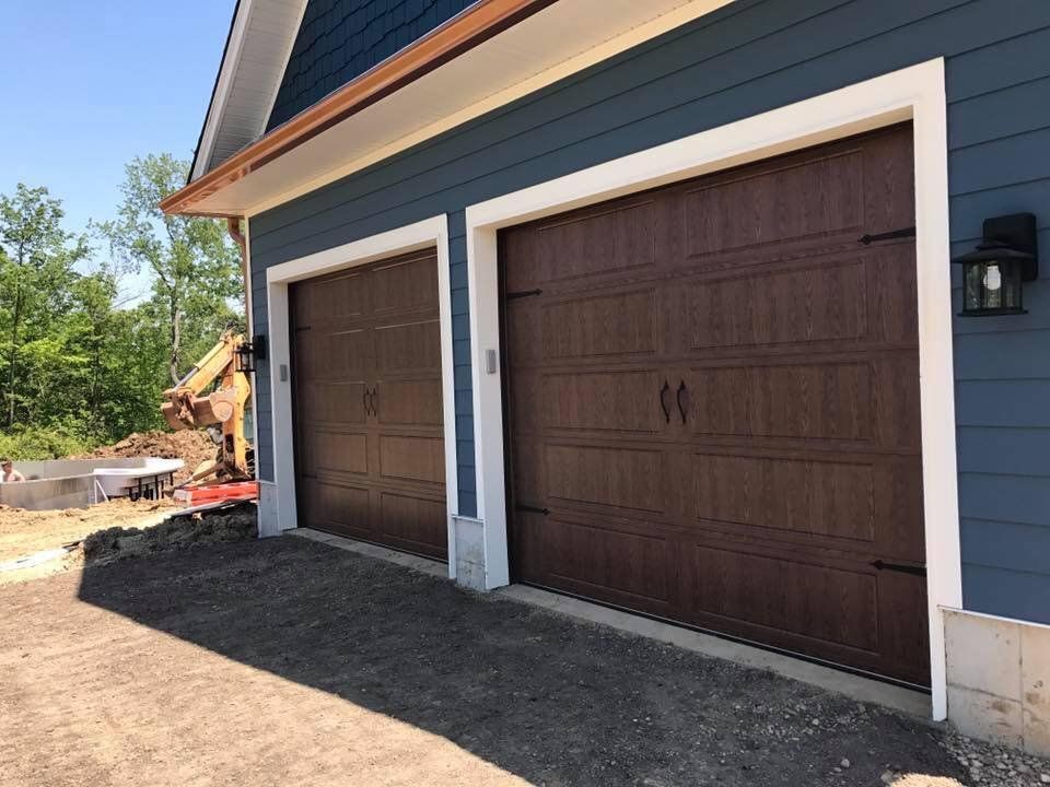 There are two garage doors on the side of a house.