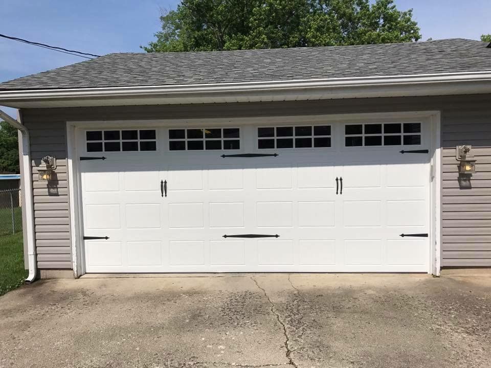 A white garage door is sitting in front of a house.