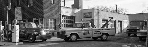 A black and white photo of a truck parked in front of a building.