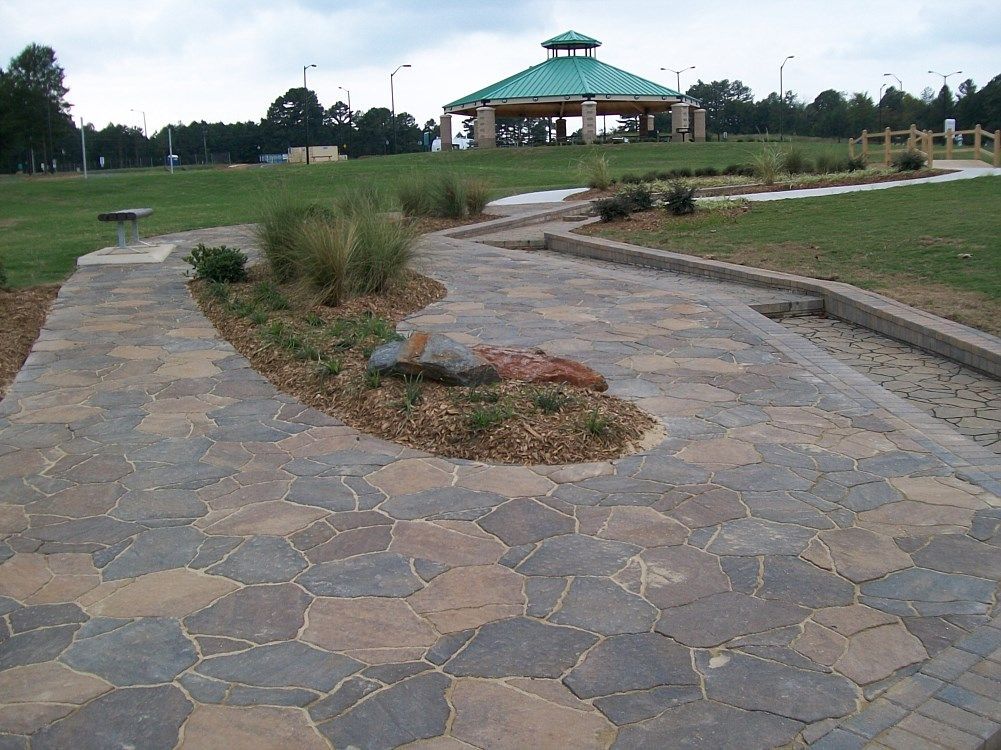 A walkway in a park with a gazebo in the background
