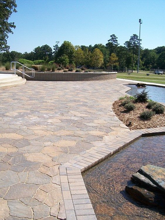 A brick walkway leading to a pond in a park