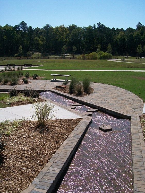 A stream running through a park with trees in the background