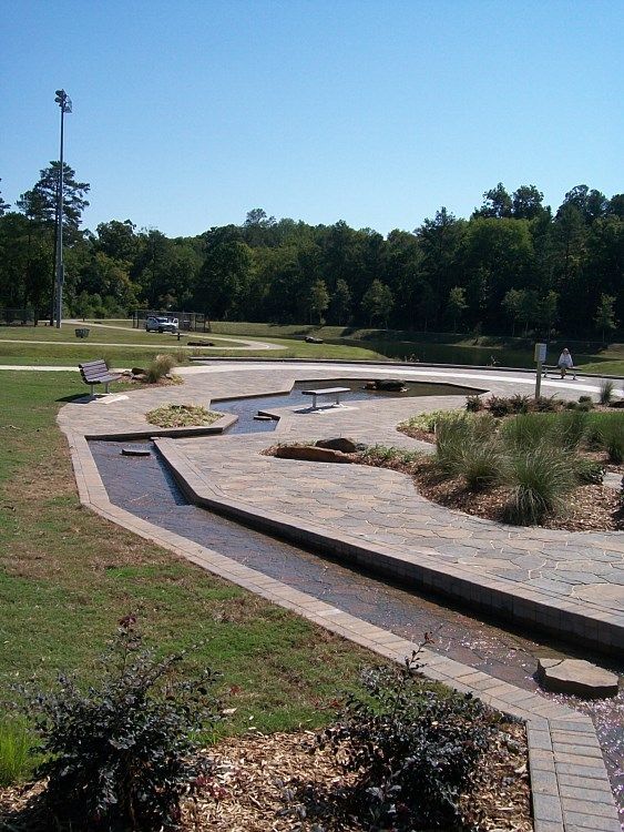 A park with a stream running through it and trees in the background