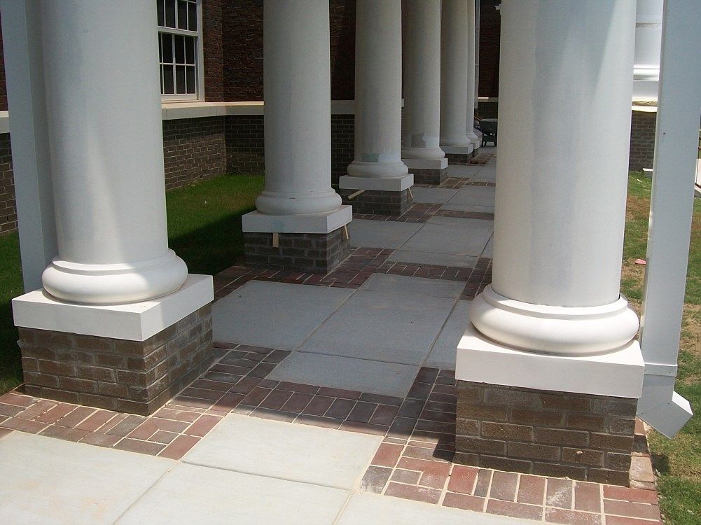 A porch with white columns and brick pillars