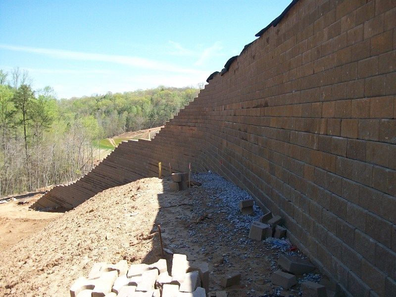 A large brick wall is being built on a hillside