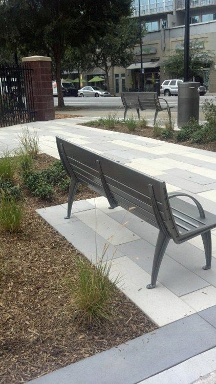 A park bench is sitting on a sidewalk in a park.