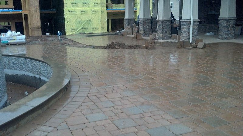A brick walkway leading to a pool in a building under construction.