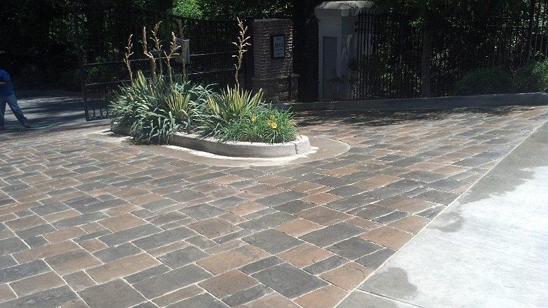 A brick driveway with a planter in the middle of it