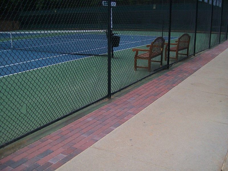 A tennis court is behind a chain link fence