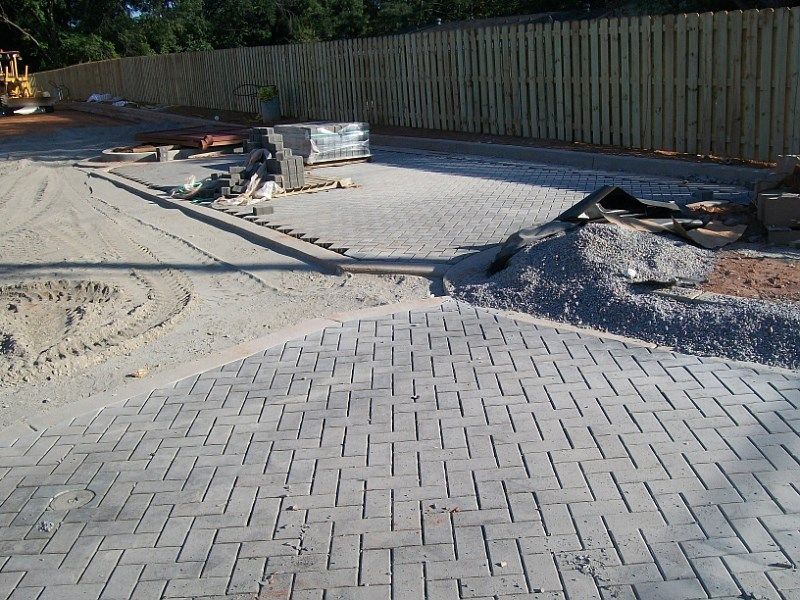 A construction site with a brick walkway and a wooden fence