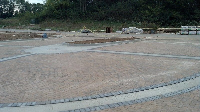 A brick driveway is being built on a construction site.