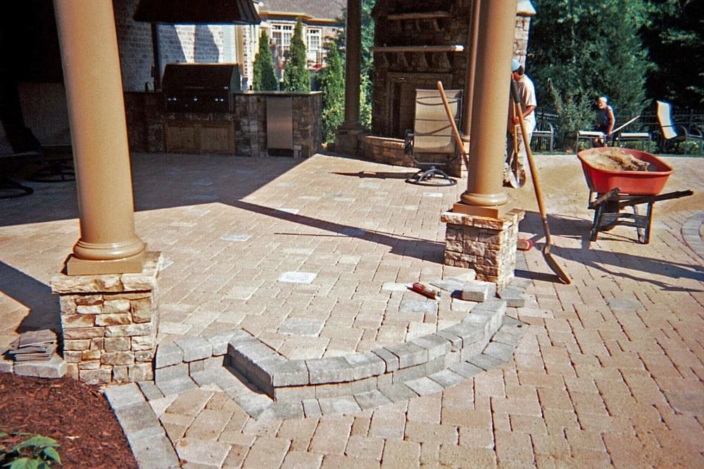 A red wheelbarrow is sitting on a brick patio