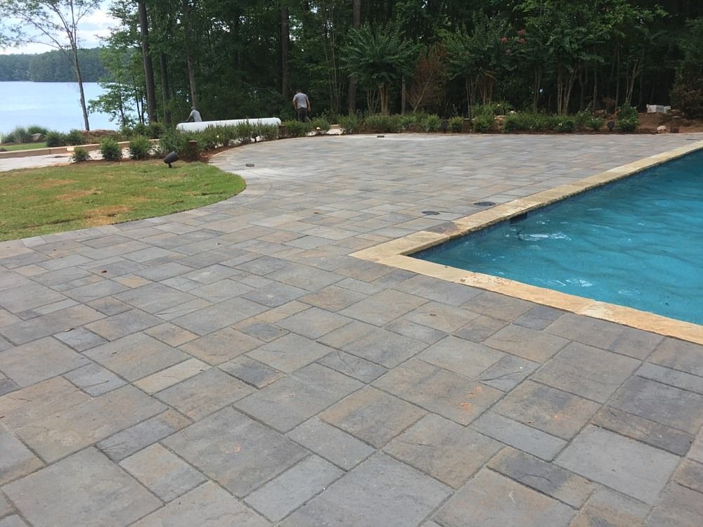 A large swimming pool with a patio in front of it