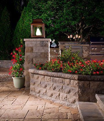 A brick wall with flowers and a lantern on top of it