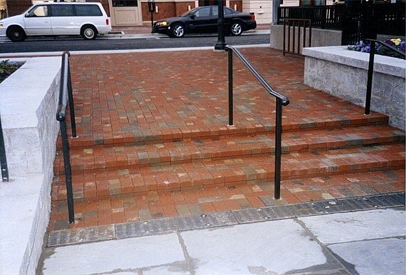 A white van is parked on the side of the road next to a set of stairs